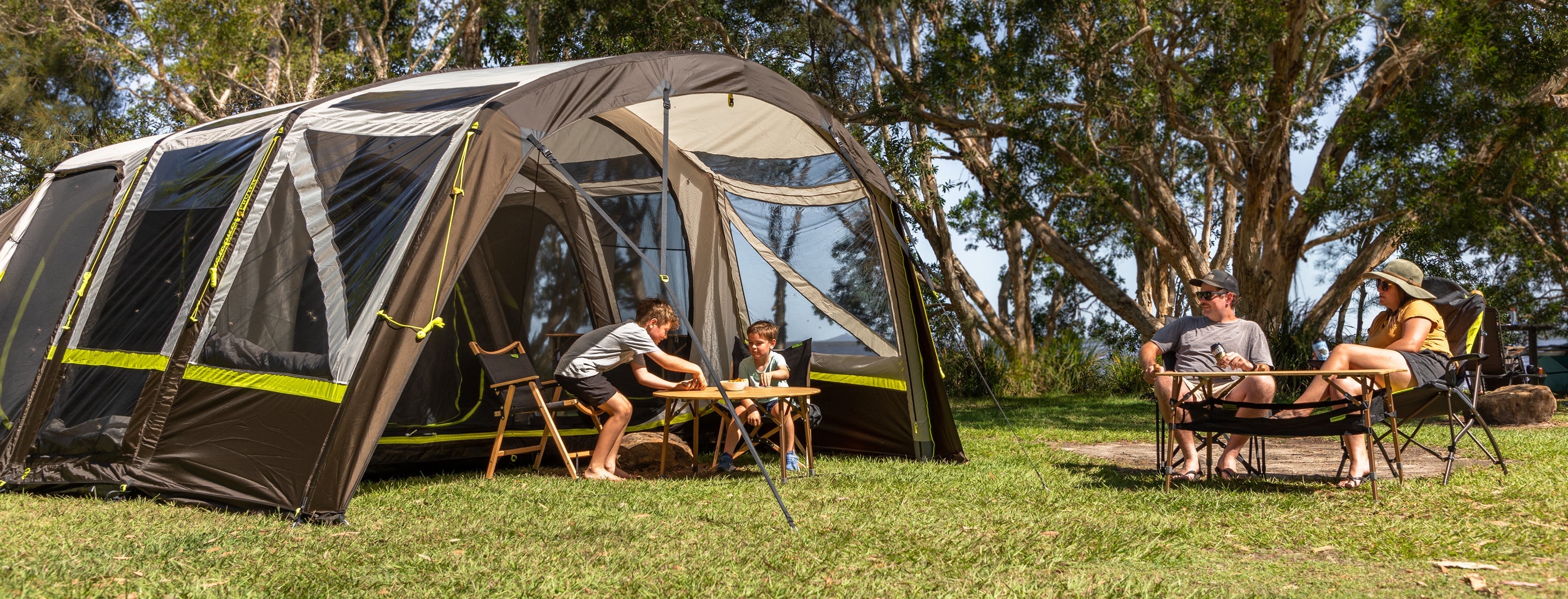 Family camping outdoors with a large tent in a natural setting
