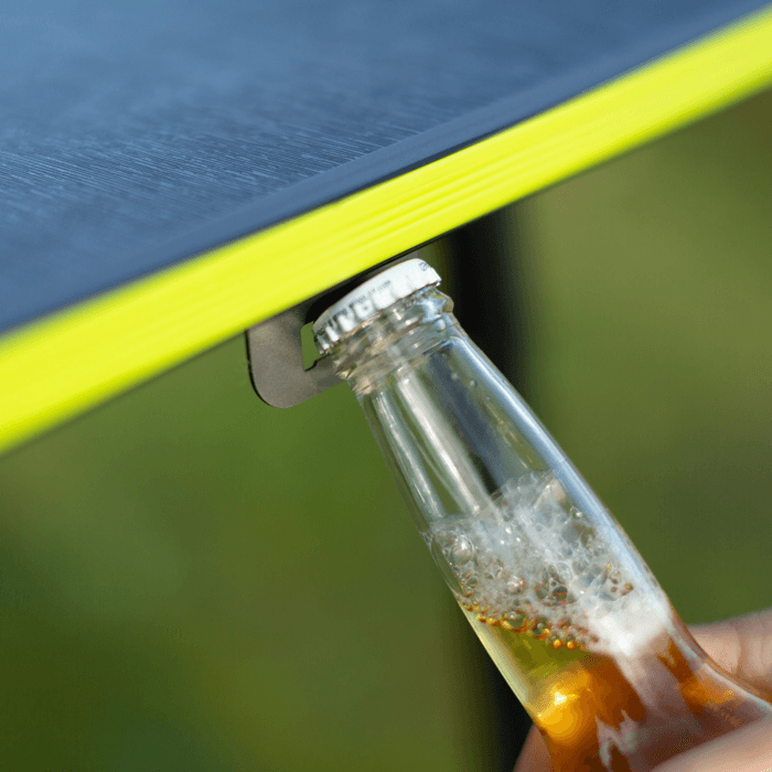 Close-up of a bottle cap being removed by the bottle opener attached to the Zempire Hexolite table
